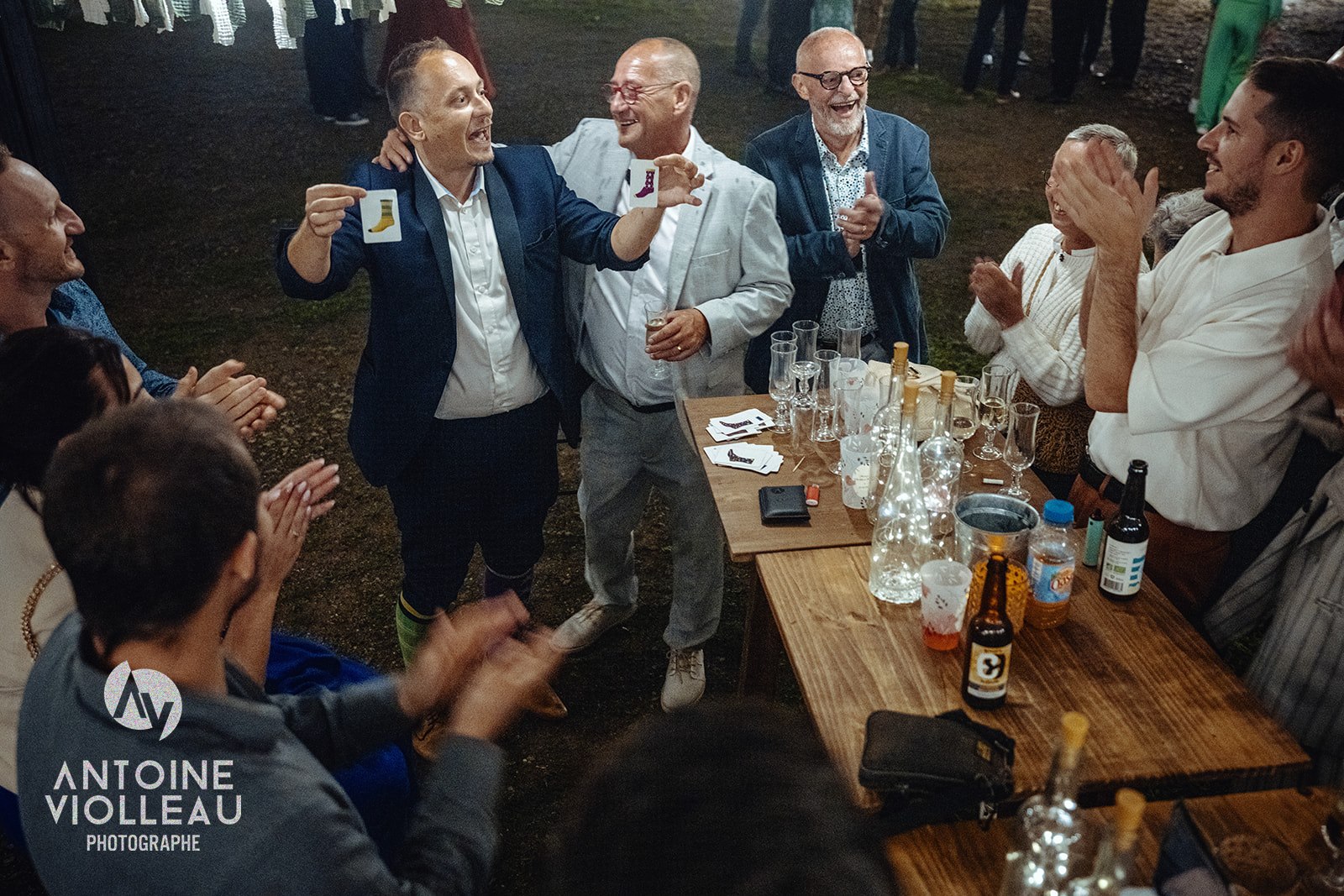 Deux invités brandissent leur carte sous les applaudissements, autour d'une table de réception